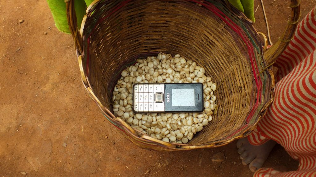 Digital tech Tanzanian farmers: a mobile phone in a woman's basket. The phone is a very old model and is well used. 