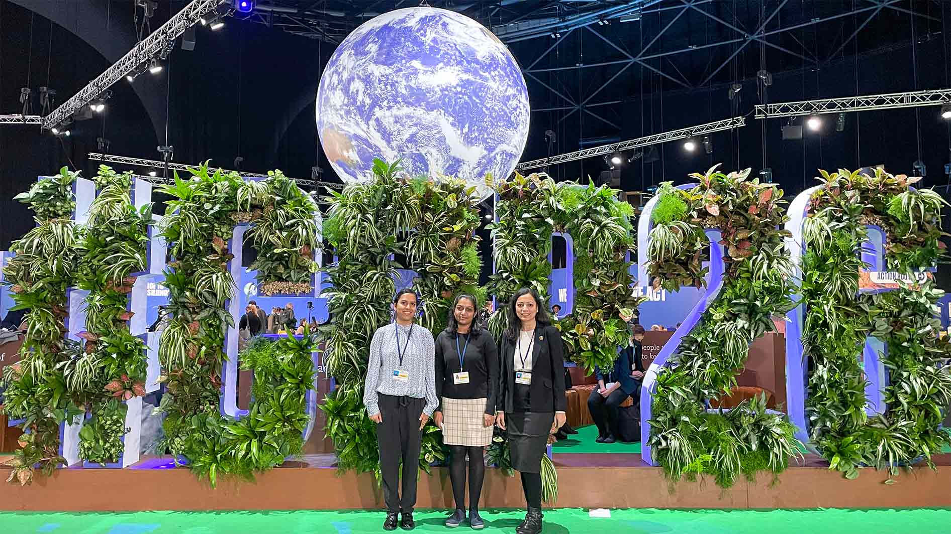 Grantham Centre people at COP26 in front of floral letters spelling COP26