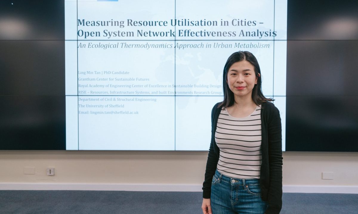 Ling Min in front of a power point presentation of her work