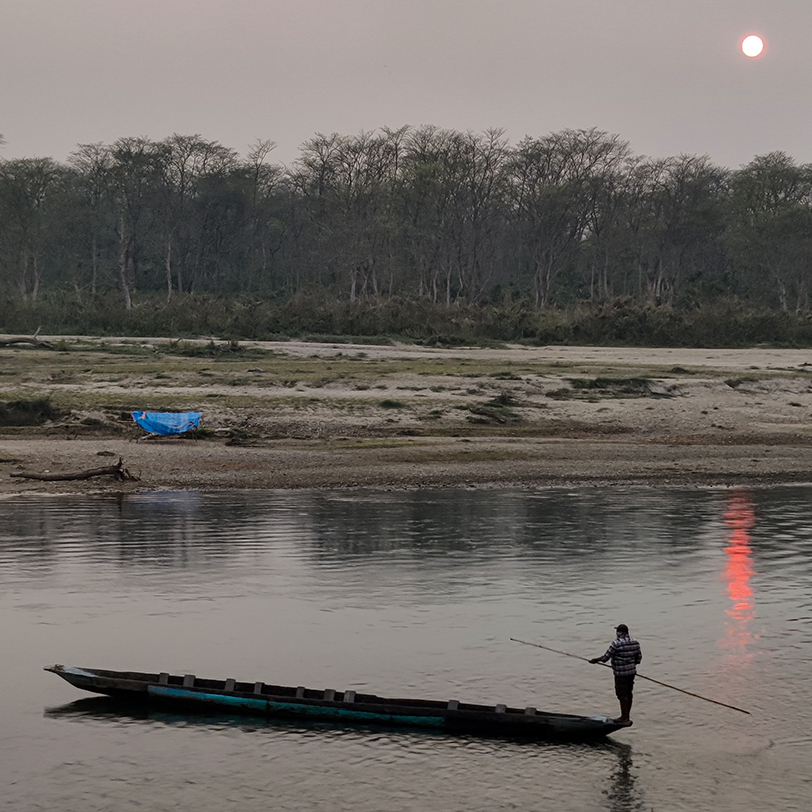 A photo of a ferry boat leaving a national park in Nepal - people are not allowed in the park overnight, showing the sometimes uneasy relations between Indigenous Lands and conservation