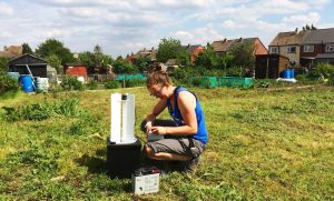 Emilie doing fieldwork with moths. We see Emilie in someone's back garden with a small moth trap.