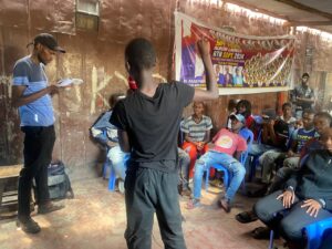 A group of locals from Mathare sitting down in a community room, listening to a speaker