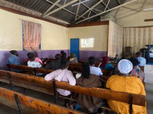 A film screening of the documentary taking place inside a community hall and attend by the local people living in Mathare
